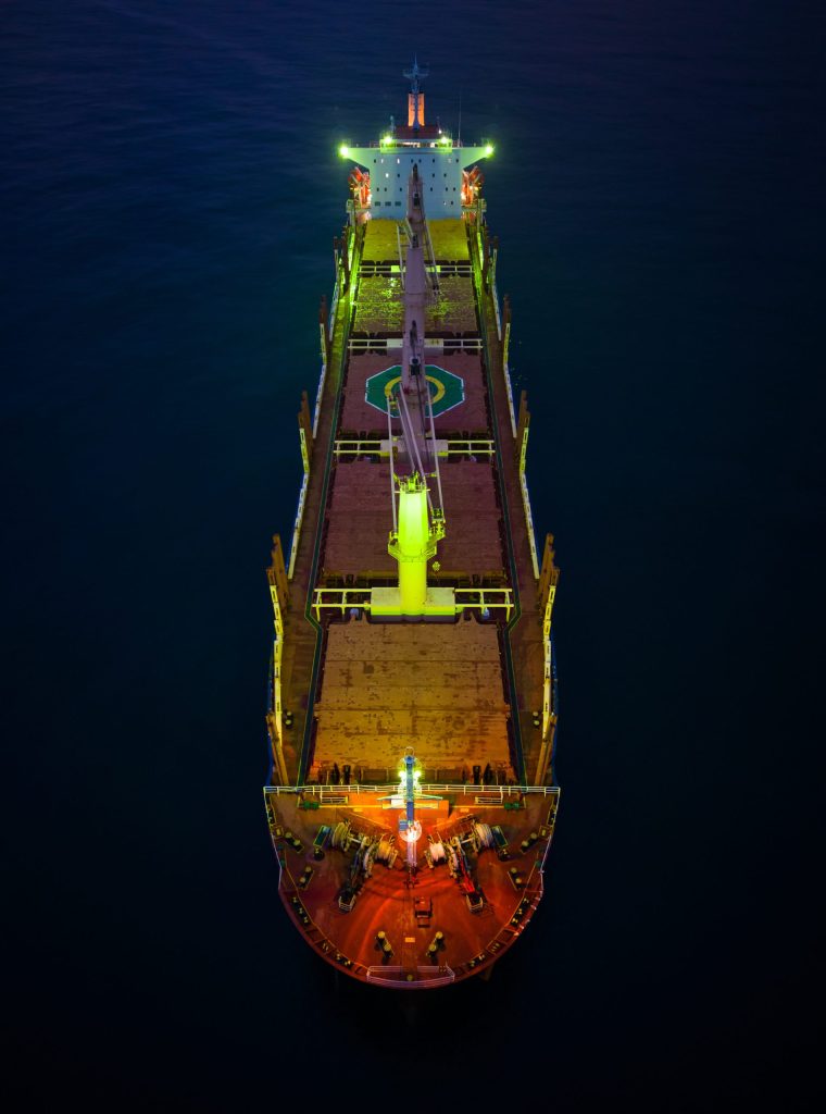 Aerial top view cargo bulk carrier ship on the sea at night